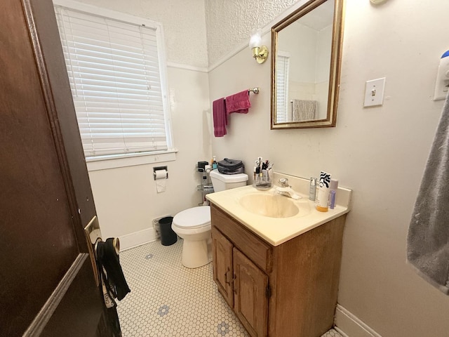 bathroom with vanity, a textured ceiling, baseboards, and toilet