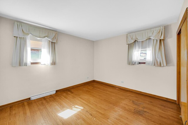 empty room with visible vents, baseboards, plenty of natural light, and wood finished floors