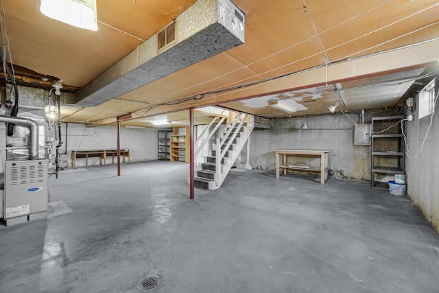 unfinished basement featuring visible vents, heating unit, stairway, and electric panel