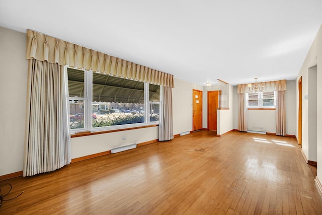 unfurnished living room featuring baseboards, visible vents, and wood finished floors