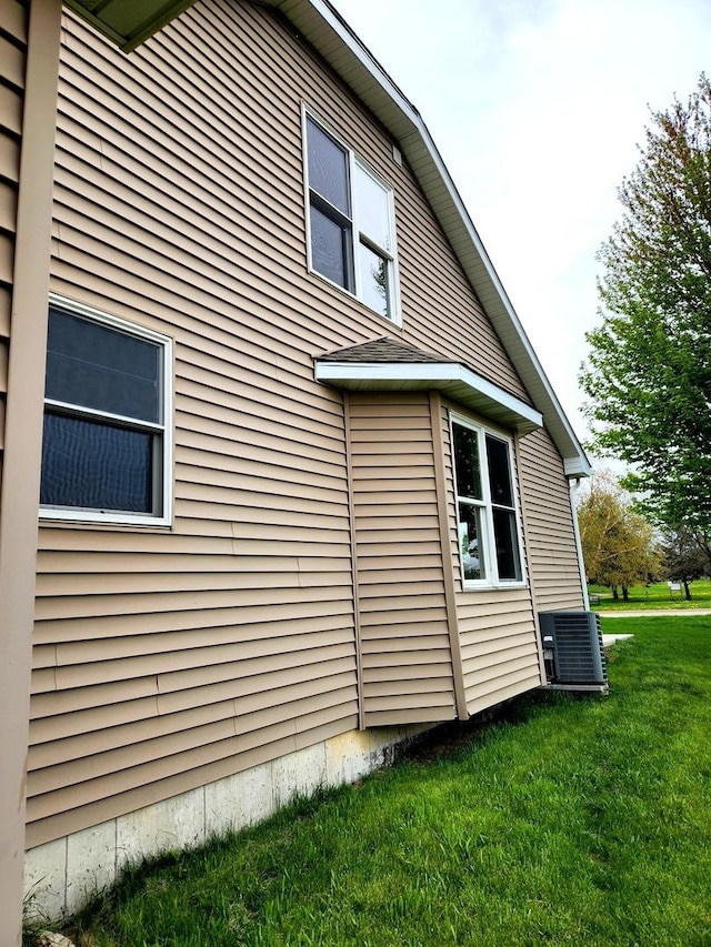 view of side of property featuring a lawn and central AC