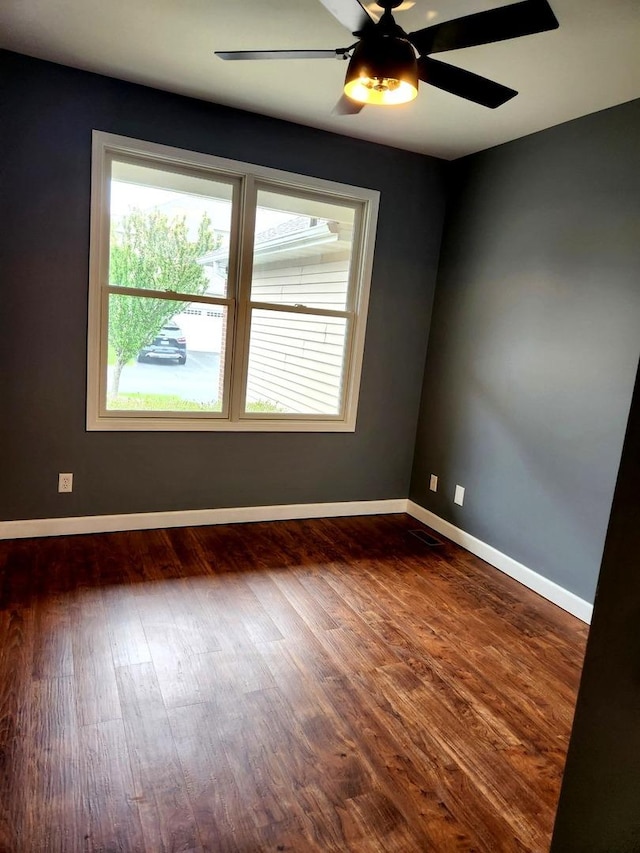 spare room with a ceiling fan, a wealth of natural light, and dark wood-type flooring