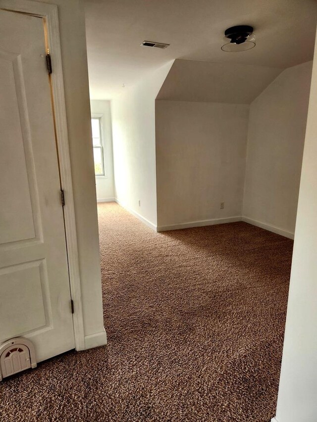 interior space featuring carpet floors, baseboards, visible vents, and lofted ceiling