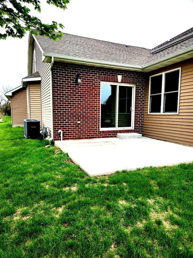 back of property with a lawn, central air condition unit, a patio area, and brick siding