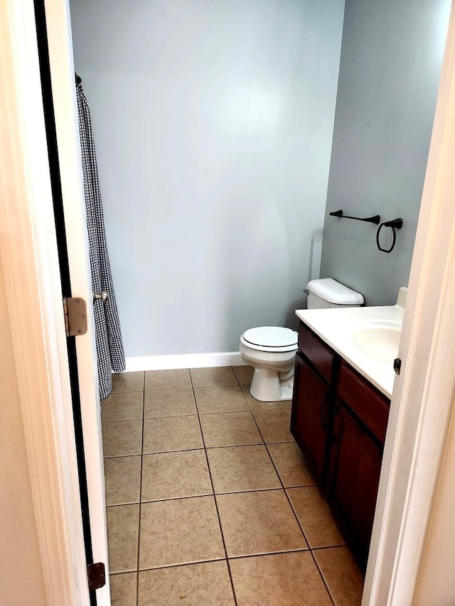 full bath with toilet, tile patterned floors, baseboards, and vanity