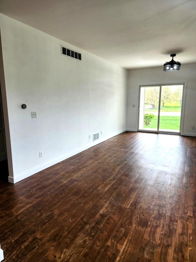 unfurnished room featuring visible vents and dark wood finished floors