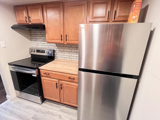 3240 N Manor Dr Unit 130, Lansing, IL 60438 - kitchen featuring decorative backsplash, under cabinet range hood, light wood-style flooring, wood counters, and stainless steel appliances