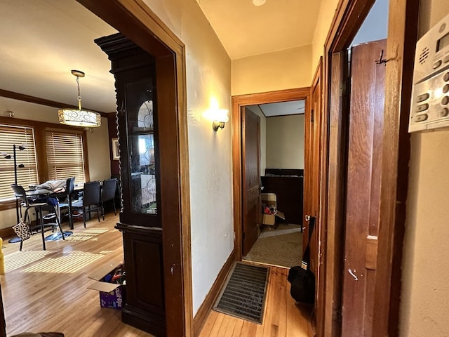 hallway with baseboards, visible vents, and wood finished floors