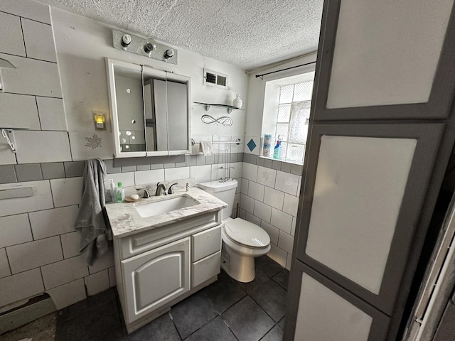 half bathroom featuring vanity, toilet, tile walls, a textured ceiling, and tile patterned floors