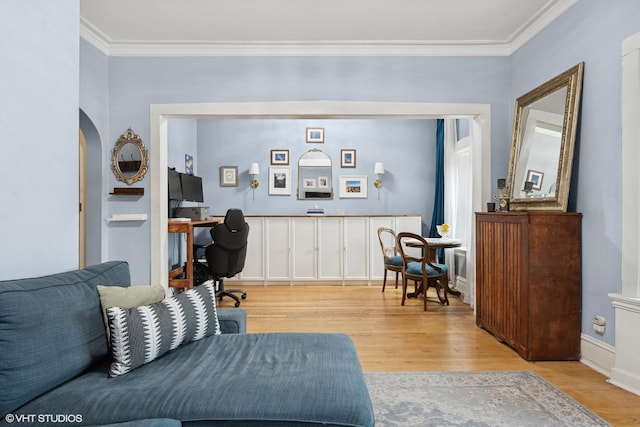 living room with ornamental molding, built in features, wood finished floors, and a warm lit fireplace