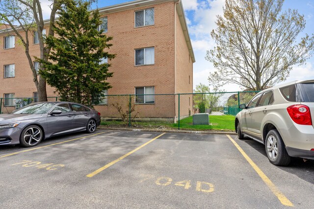 704 Cobblestone Cir Unit D, Glenview, IL 60025 - uncovered parking lot featuring fence