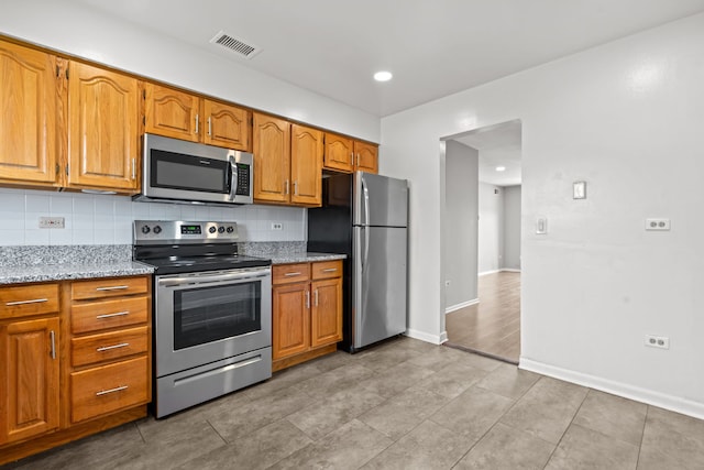 704 Cobblestone Cir Unit D, Glenview, IL 60025 - kitchen with visible vents, tasteful backsplash, light stone countertops, baseboards, and stainless steel appliances