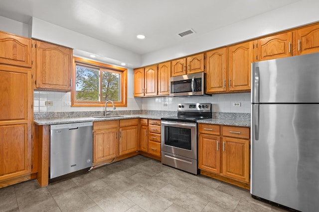 704 Cobblestone Cir Unit D, Glenview, IL 60025 - kitchen featuring brown cabinetry, visible vents, appliances with stainless steel finishes, tasteful backsplash, and a sink