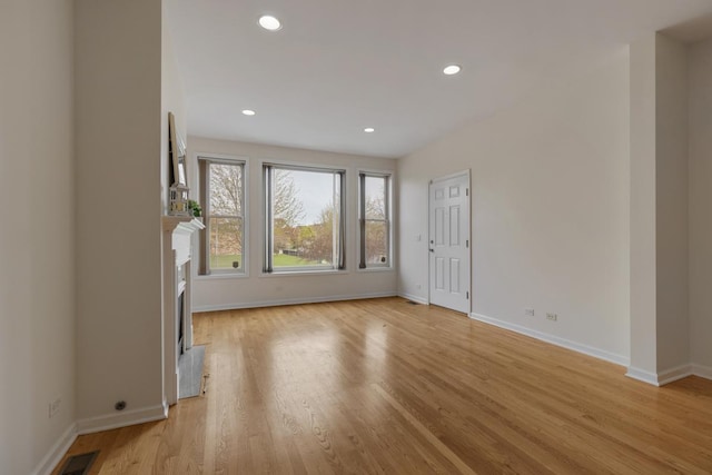unfurnished living room with recessed lighting, baseboards, a high end fireplace, and light wood-type flooring