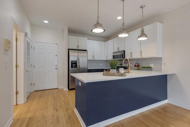 kitchen featuring light countertops, appliances with stainless steel finishes, white cabinets, and a peninsula