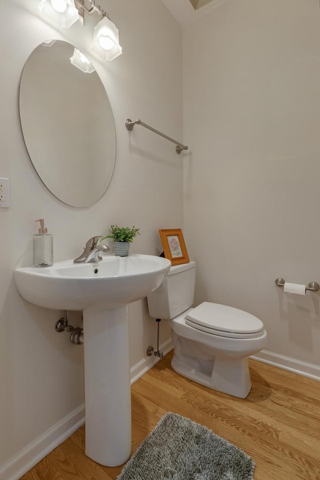 bathroom featuring a sink, baseboards, toilet, and wood finished floors