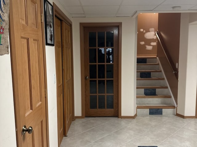 interior space with tile patterned floors, baseboards, and a paneled ceiling