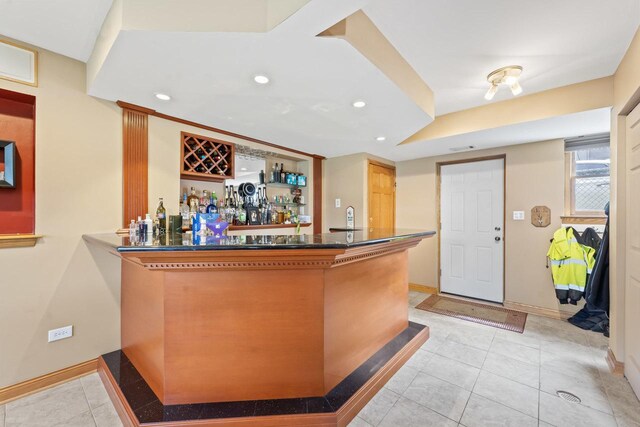 bar featuring recessed lighting, baseboards, light tile patterned floors, and a bar