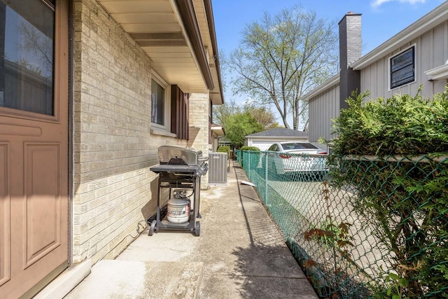 exterior space with fence, central AC, and brick siding