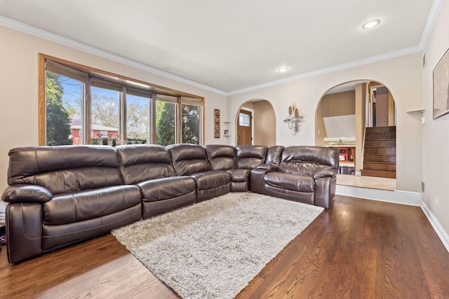 living area featuring crown molding, arched walkways, dark wood finished floors, baseboards, and stairway