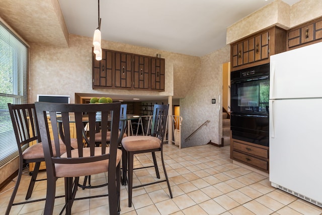 kitchen featuring freestanding refrigerator, oven, light tile patterned flooring, and a warming drawer