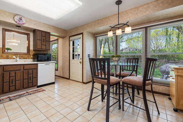 kitchen featuring white dishwasher, a sink, black microwave, light tile patterned flooring, and light countertops