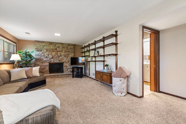 living room with light carpet, a fireplace, baseboards, and washer / dryer