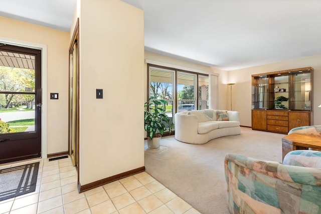 living room featuring light tile patterned floors, baseboards, and light colored carpet