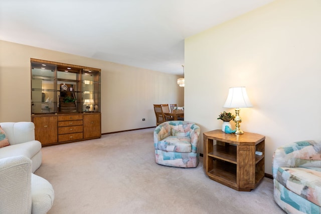carpeted living area with a chandelier and baseboards