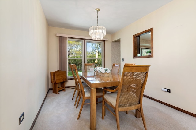 dining room featuring a chandelier, light colored carpet, and baseboards