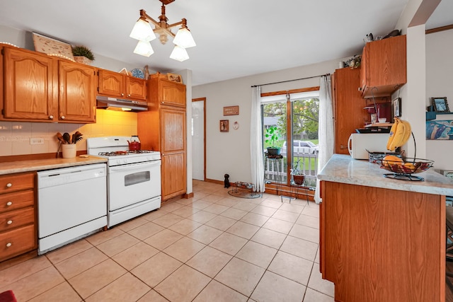 kitchen featuring white appliances, under cabinet range hood, light countertops, backsplash, and brown cabinets