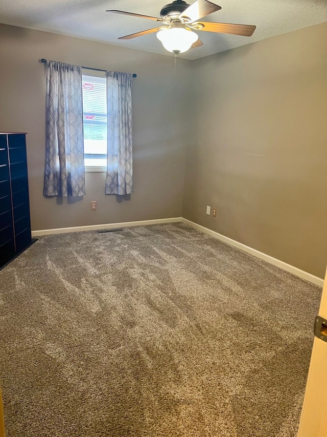 unfurnished room with carpet floors, a ceiling fan, and baseboards