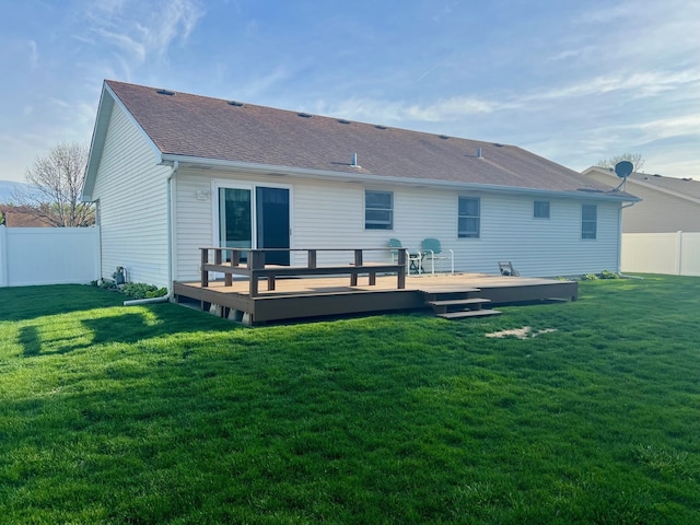 rear view of property featuring a yard, a wooden deck, a fenced backyard, and roof with shingles
