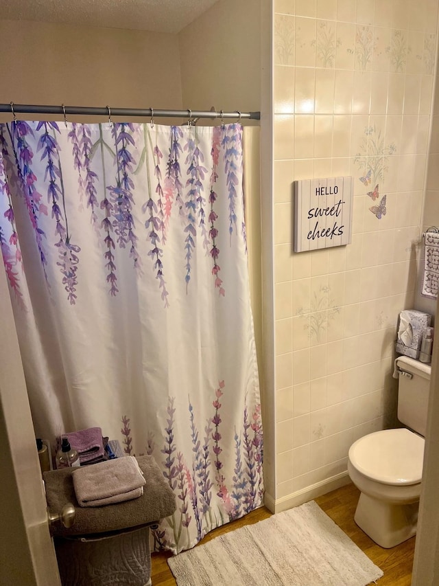 full bath with a shower with shower curtain, toilet, and wood finished floors