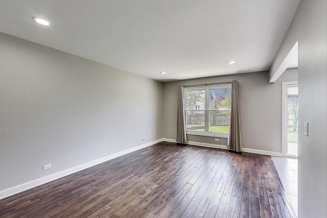 spare room with dark wood-style flooring, baseboards, and recessed lighting