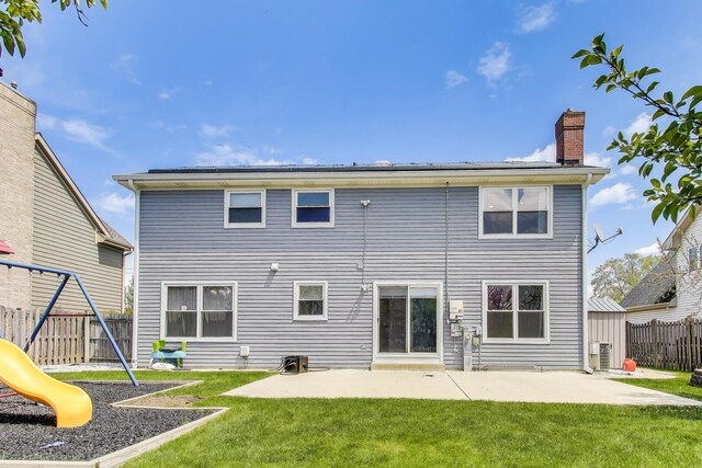 back of property with a patio area, a chimney, and a playground