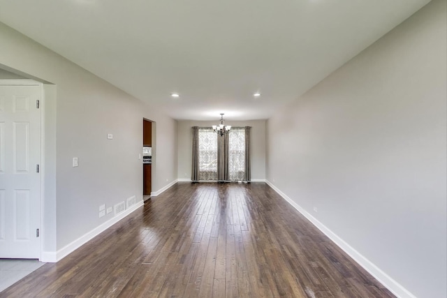 unfurnished living room featuring a chandelier, dark wood-style floors, baseboards, and recessed lighting