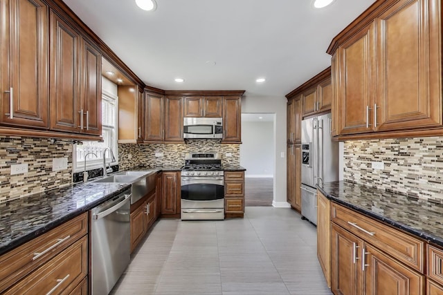kitchen with stainless steel appliances, backsplash, dark stone counters, recessed lighting, and a sink
