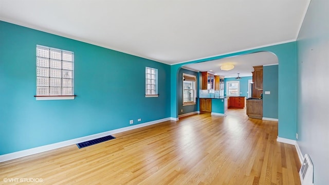 1730 Madison St, Evanston, IL 60202 - unfurnished living room featuring arched walkways, baseboards, healthy amount of natural light, light wood-style flooring, and ornamental molding