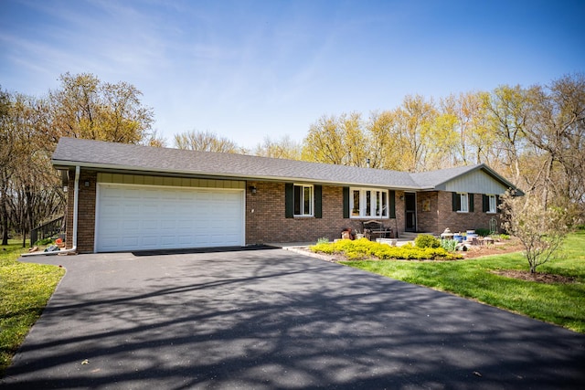 single story home featuring brick siding, an attached garage, and aphalt driveway