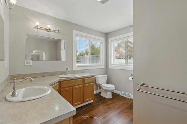 full bathroom featuring double vanity, a sink, toilet, and hardwood / wood-style floors