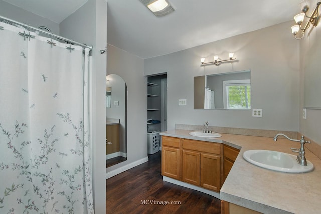 bathroom featuring double vanity, a sink, a shower with shower curtain, and wood finished floors