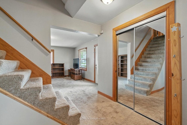 foyer with baseboards, carpet, and stairs