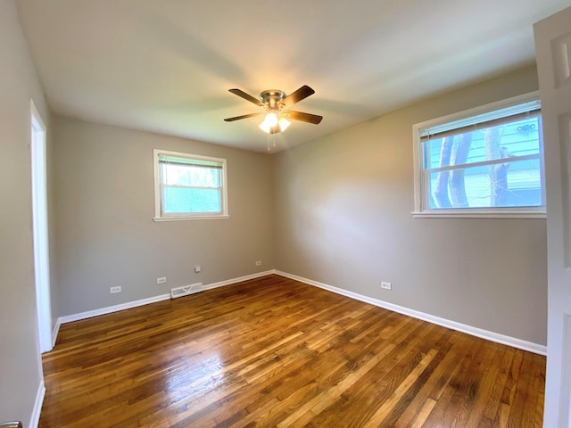 unfurnished room featuring baseboards, a ceiling fan, dark wood finished floors, and visible vents