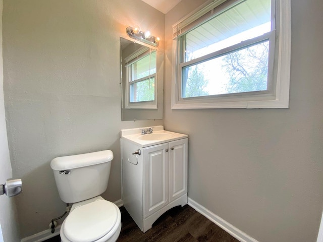 half bathroom with baseboards, wood finished floors, toilet, and vanity