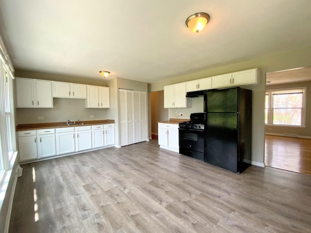 kitchen featuring baseboards, white cabinets, black appliances, and light wood finished floors