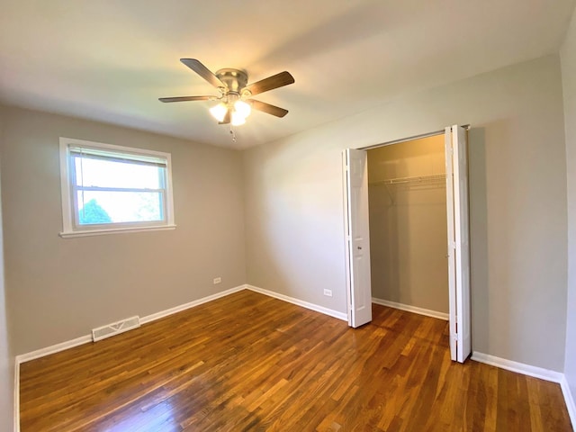 unfurnished bedroom with ceiling fan, visible vents, wood finished floors, baseboards, and a closet