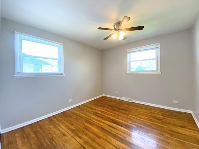 spare room featuring baseboards, ceiling fan, wood finished floors, and visible vents