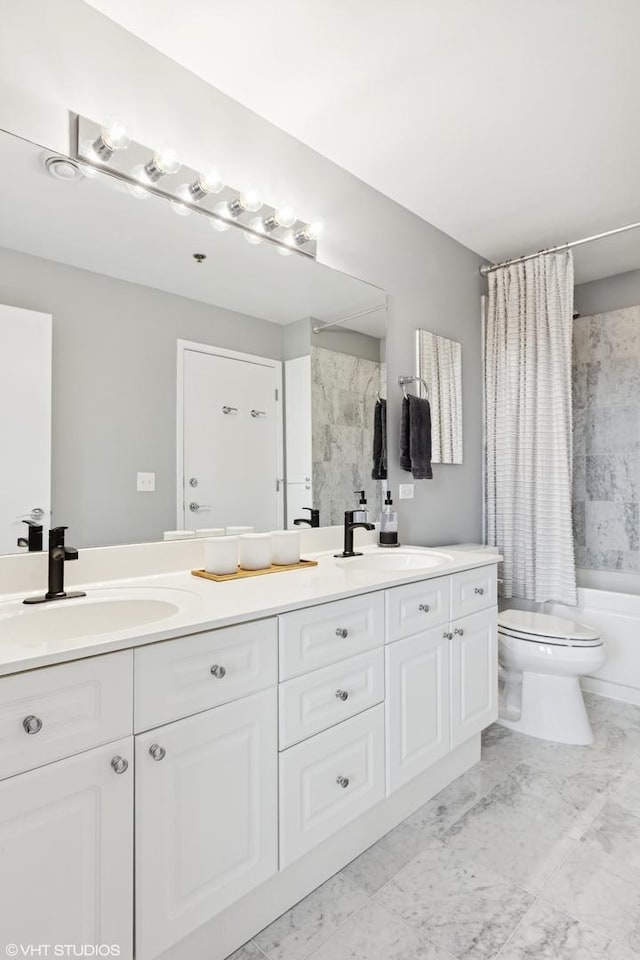 bathroom featuring double vanity, toilet, and a sink