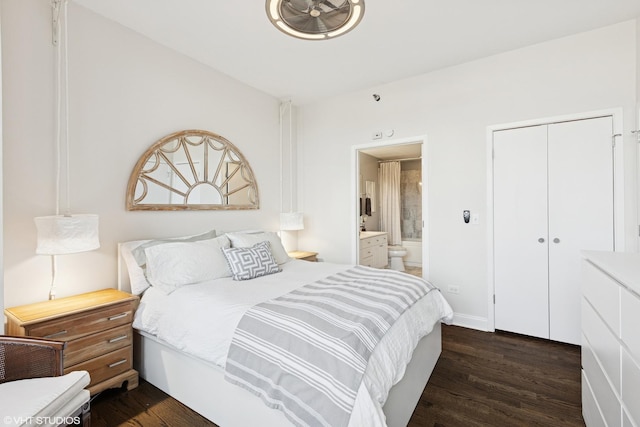 bedroom featuring a closet, baseboards, ensuite bath, and dark wood-style floors